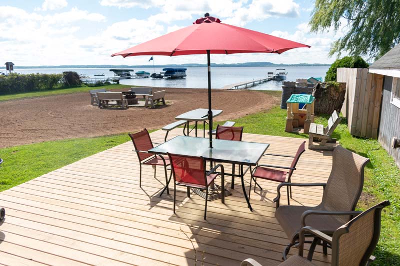 outdoor table on deck with four chairs and a red umbrella